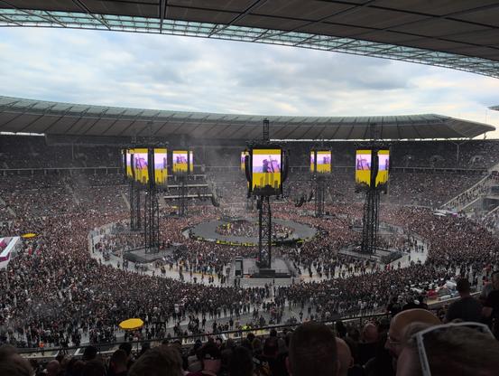 Eine runde Bühne im Innenraum des Olympiastadions Berlin. Es spielt eine Band, das Stadion ist noch nicht ganz voll.